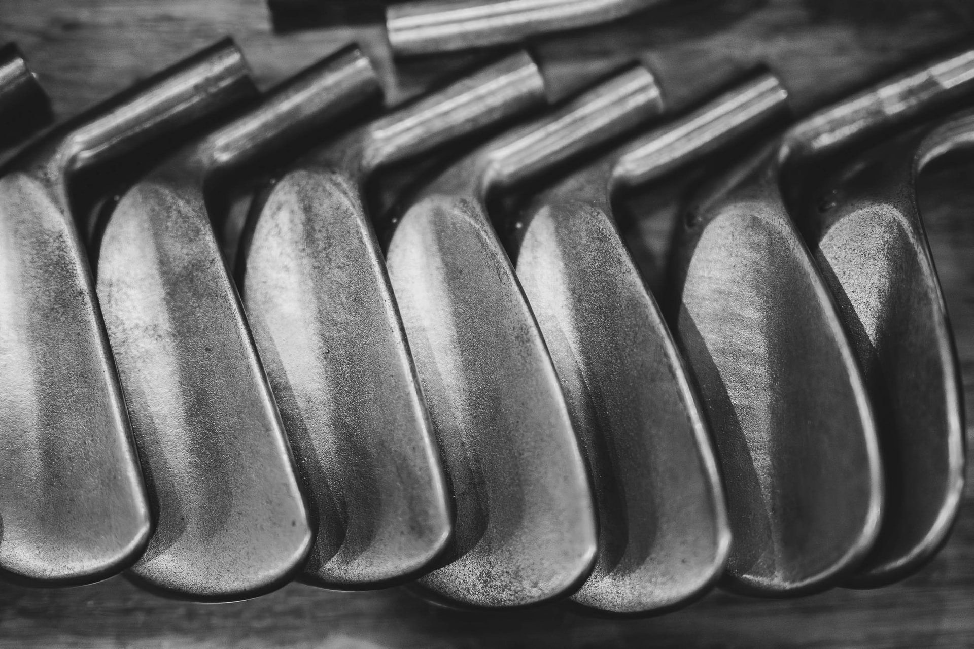 A row of worn blade iron heads laid side by side on a bench, close up in black and white