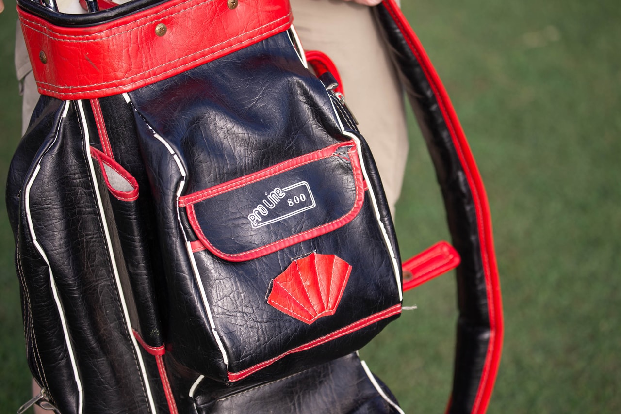 Close on an old black and red vinyl golf bag, its pocket marked Pro Line 800